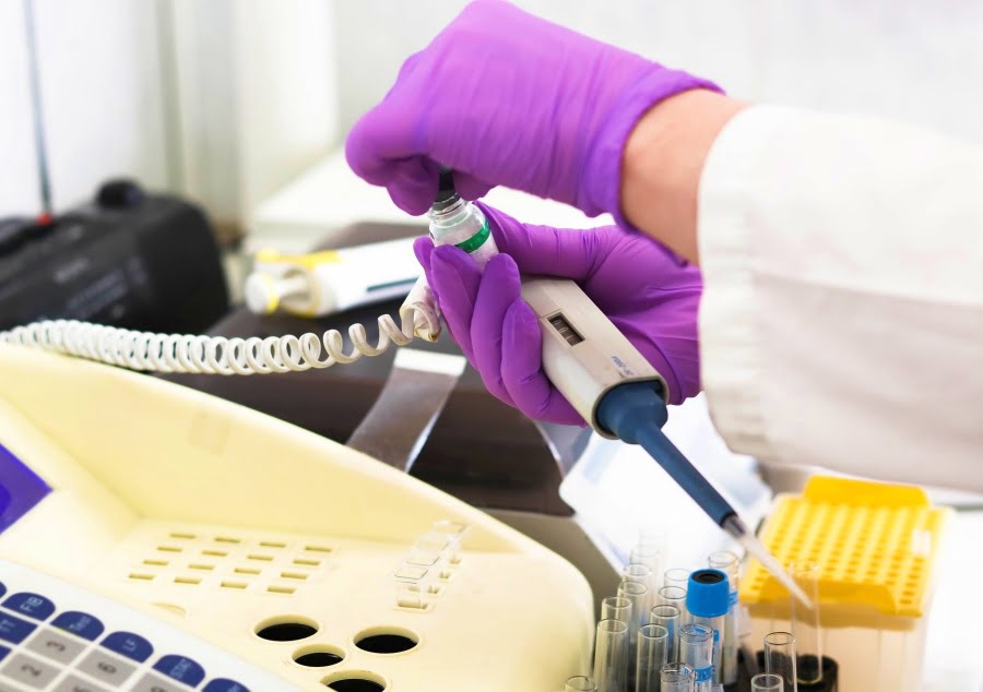 Labeling Medical Devices. hands wearing medical gloves holding thermometer and filling a vial
