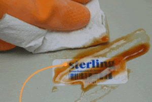 tool tracking labels. hand wiping spilled oil off of a laminated label