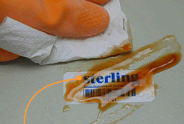 tool tracking labels. hand wiping spilled oil off of a laminated label