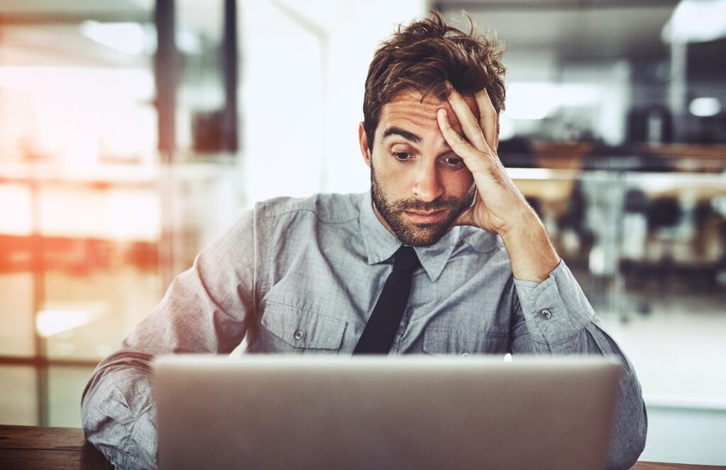 Businessman, laptop and headache in stress, burnout or overworked from strain at the office desk. Frustrated man person or employee with bad head pain or confused working on computer at the workplace.